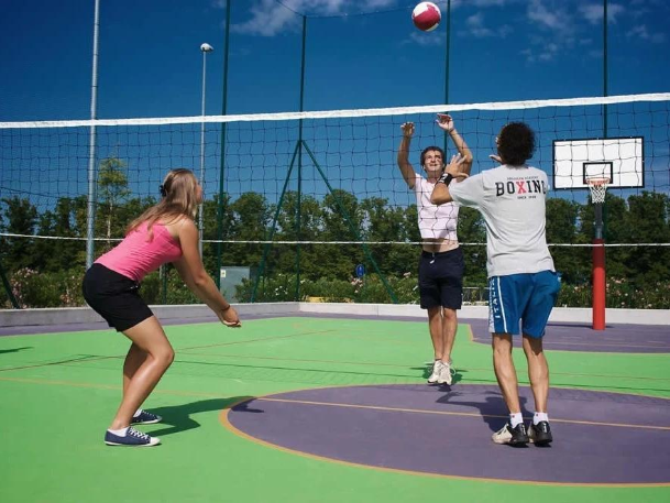 Group of players jumping and hitting a volleyball over a net on a colorful outdoor court during a court installation service in Chandler, AZ