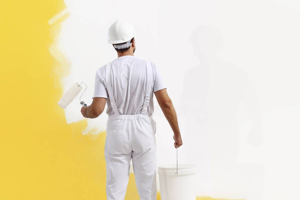 A professional painter working on adding warm yellow paint to a wall at All About Painting near Johnson City, Tenne