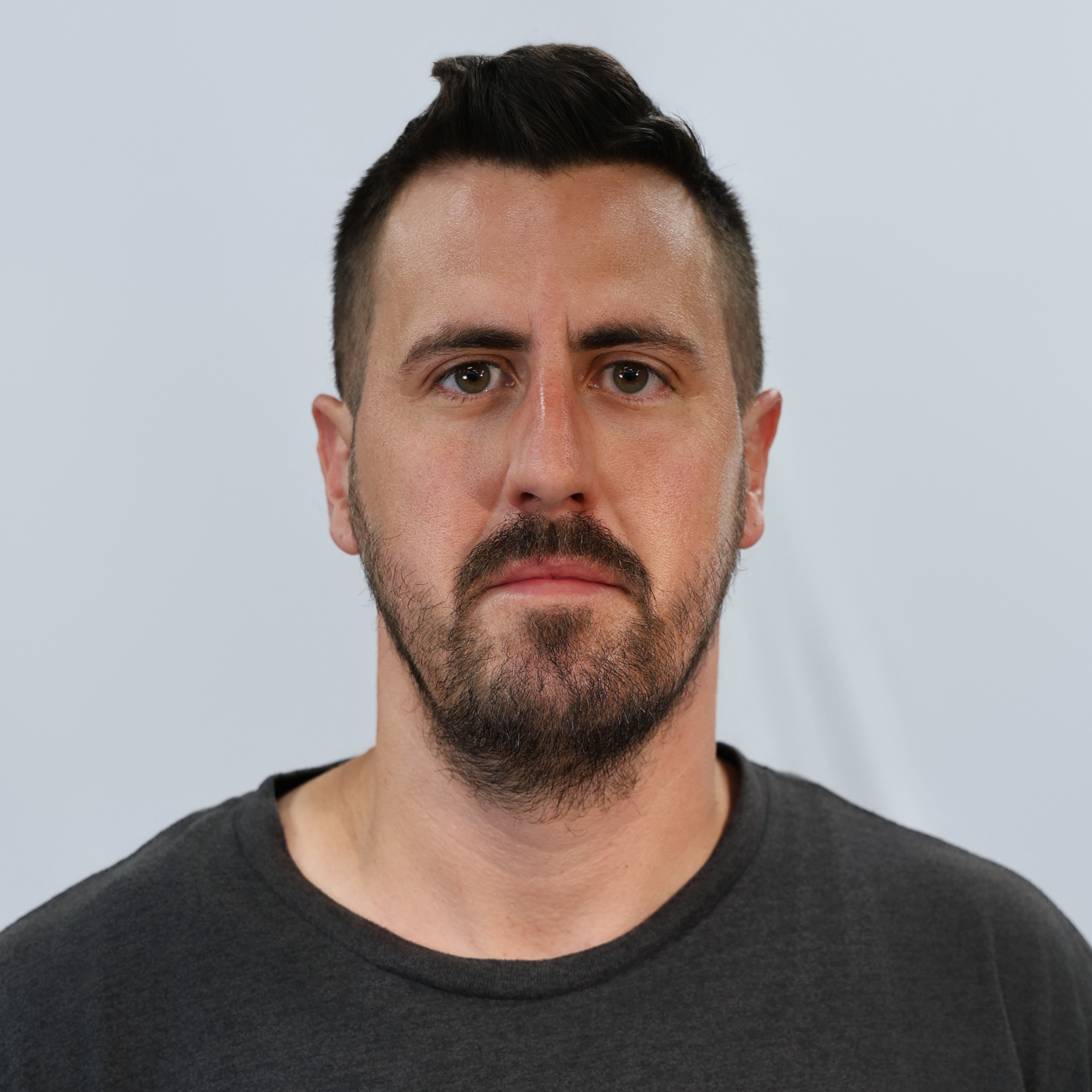 A man with a beard and mustache is wearing a black shirt and looking at the camera.