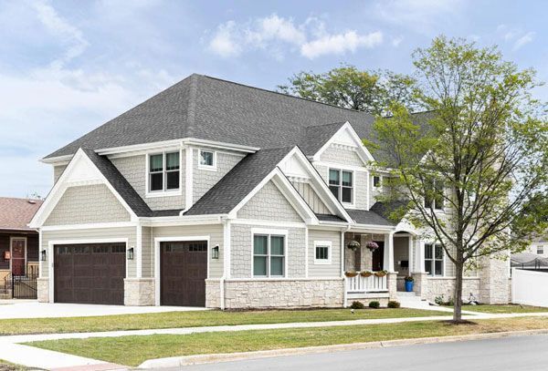 a large white house with a gray roof and two garages