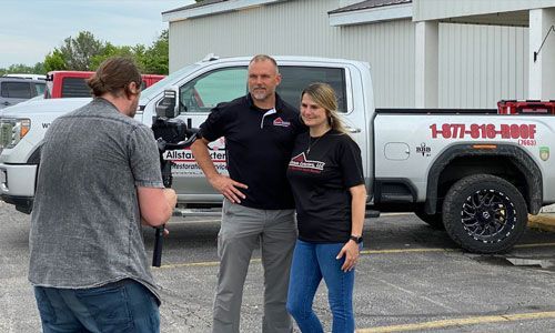 a man is taking a picture of a man and woman in front of a truck