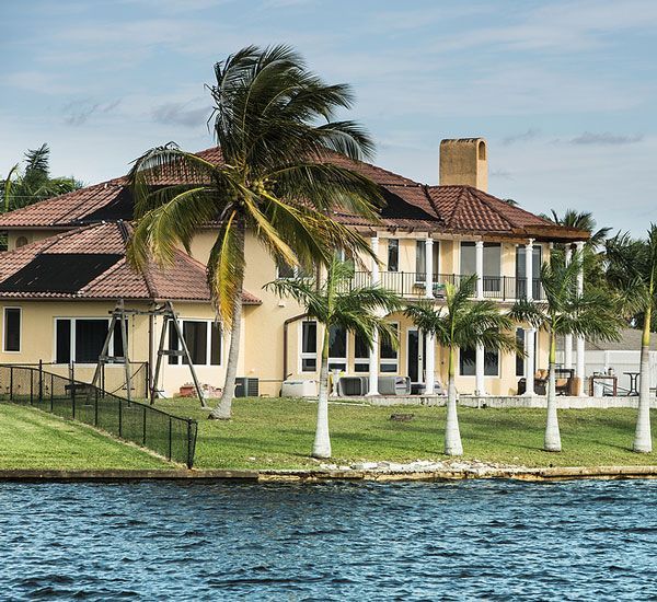 A waterfront home in Cape Coral, Florida with a tile roof and palm trees