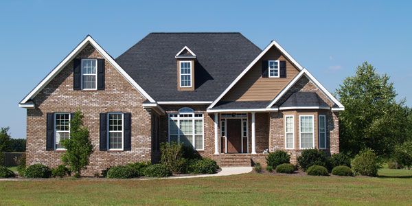 a large brick house with a black asphalt shingle roof and white shutters
