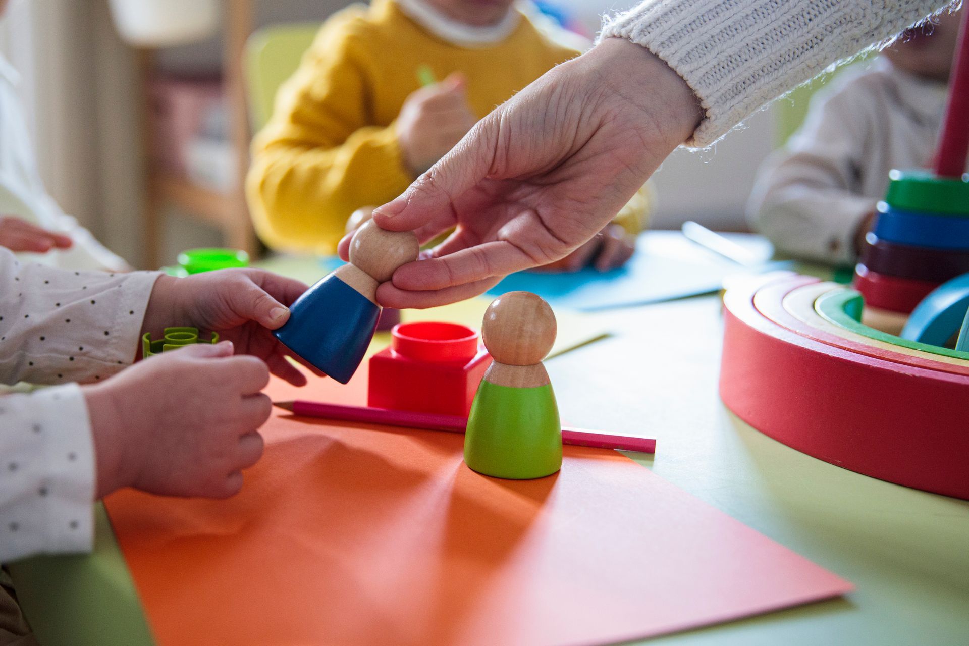 A group of children are playing with wooden toys at a table.