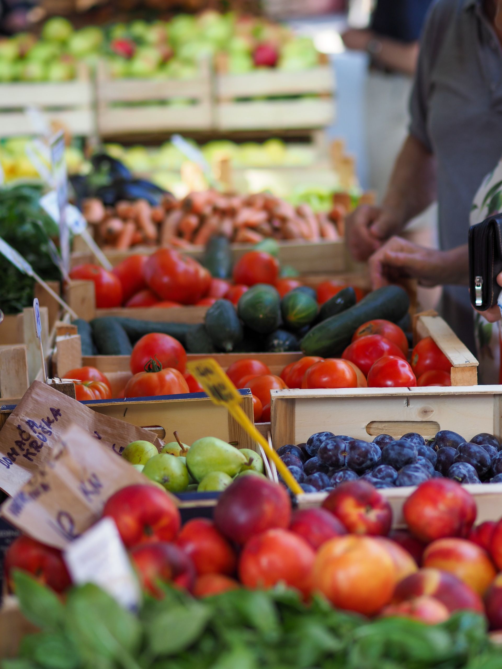 Market stall with crates of colorful fresh fruit, including apples, peaches, plums, and grapes