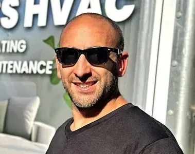 A man wearing sunglasses is smiling in front of a sign that says hvac maintenance