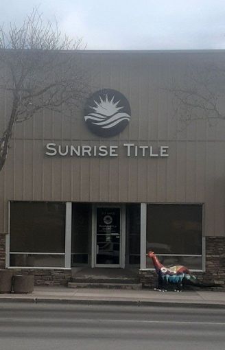Sunrise Title storefront with gray facade and a lawn ornament near the entrance