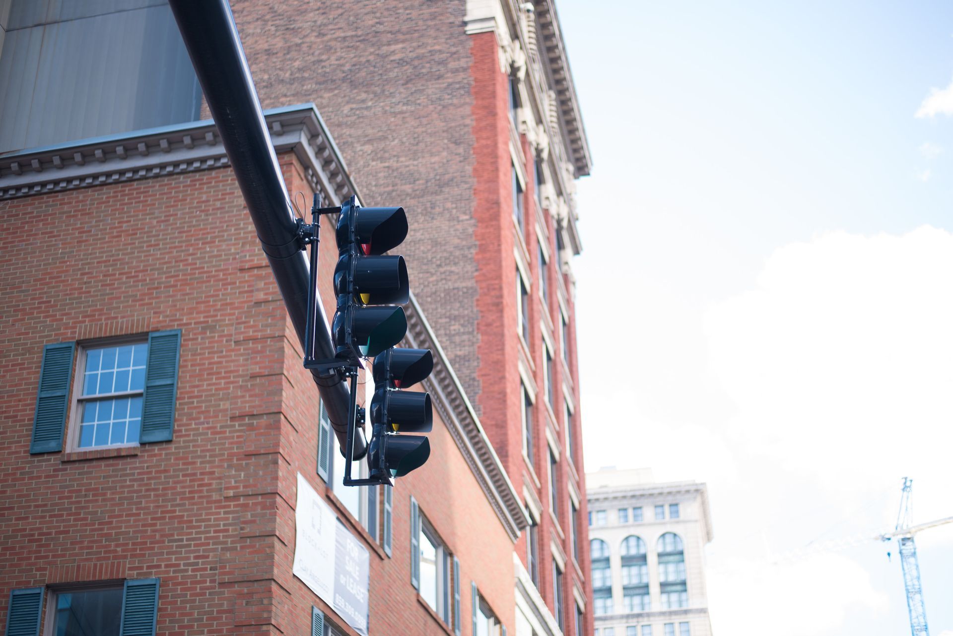 Picture of a red traffic light with a brick building and blue sky in the background.