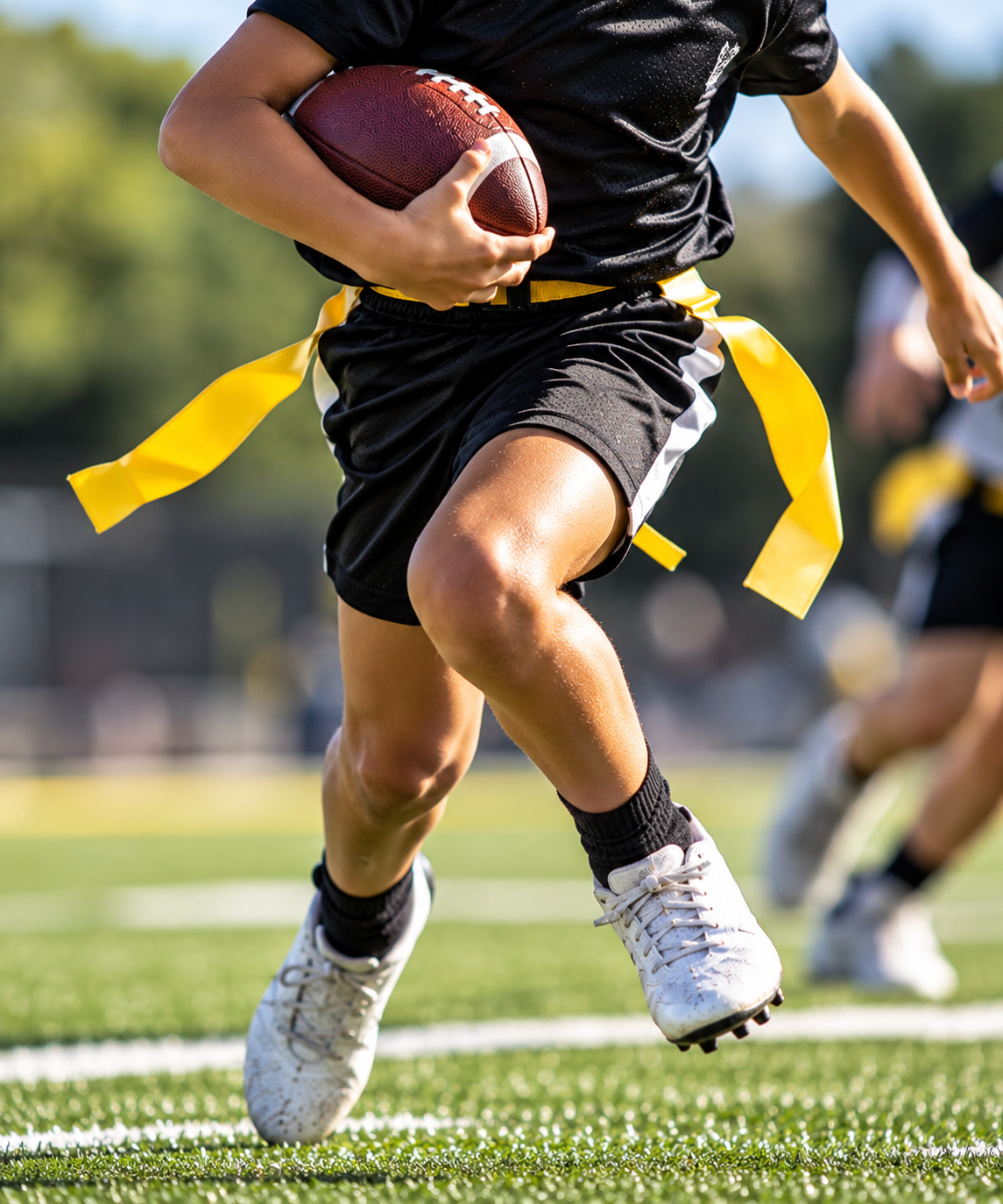 Football player in maroon jersey holding ball, smiling, surrounded by teammates on a field.