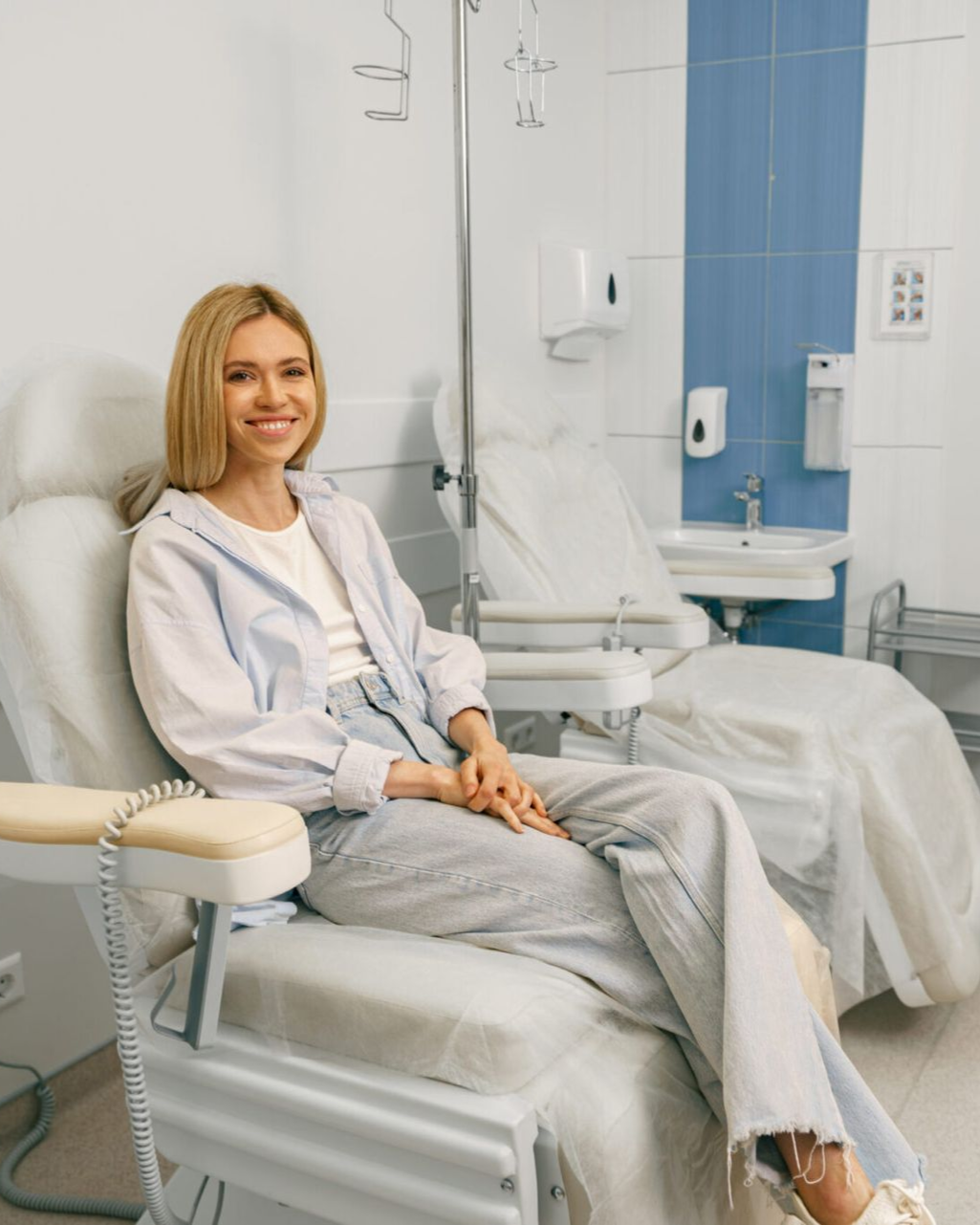 Woman sitting in a dental chair in a bright clinic, smiling at the camera.