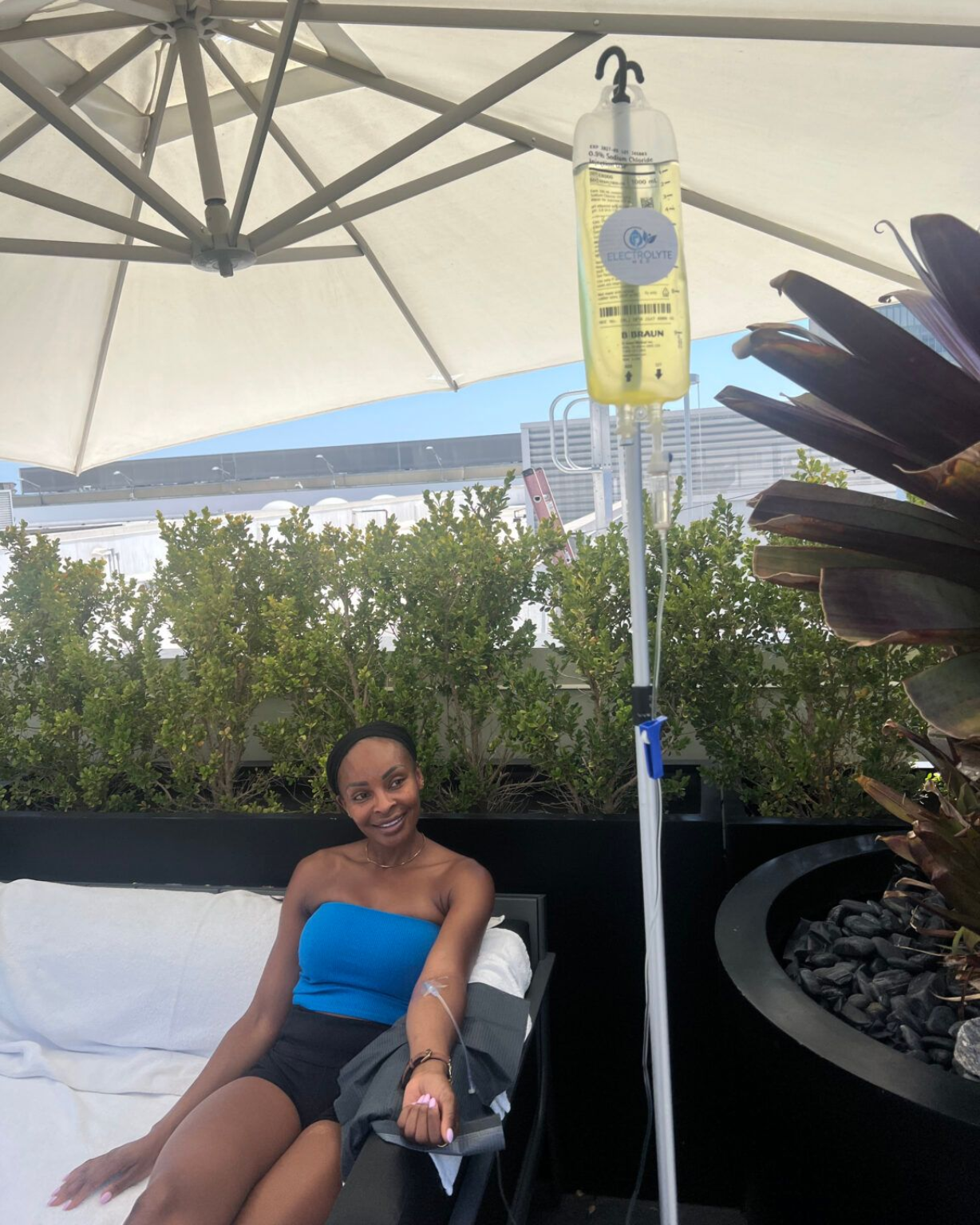 Woman relaxing in a lounge chair under a canopy beside an IV drip stand outdoors