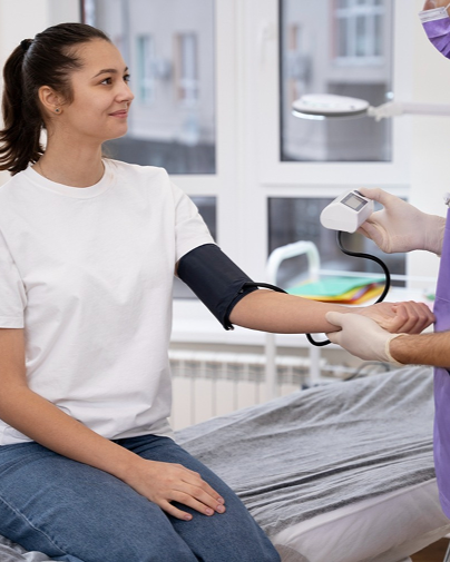Patient seated while clinician uses a handheld device on her arm in a medical exam room.