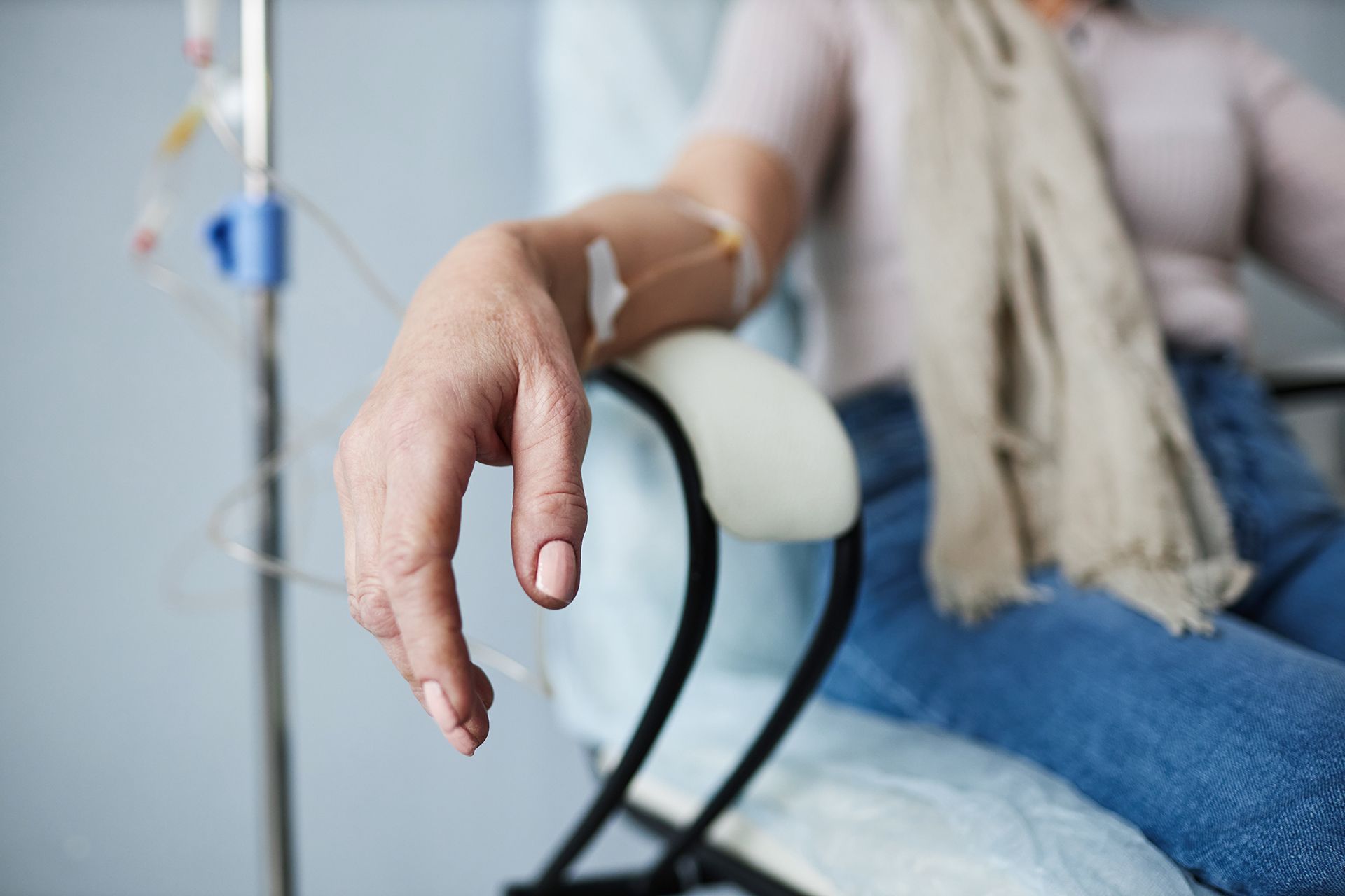 Patient resting in a hospital bed with an IV line in the hand