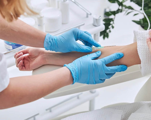 Gloved clinician taking a patient’s pulse in a bright medical exam room
