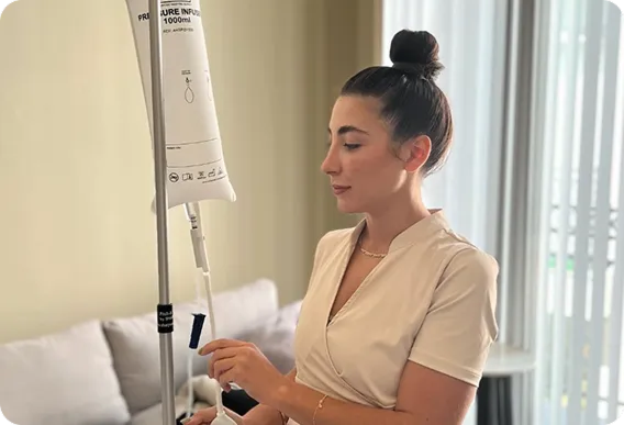 Woman adjusting an IV drip in a bright hospital room
