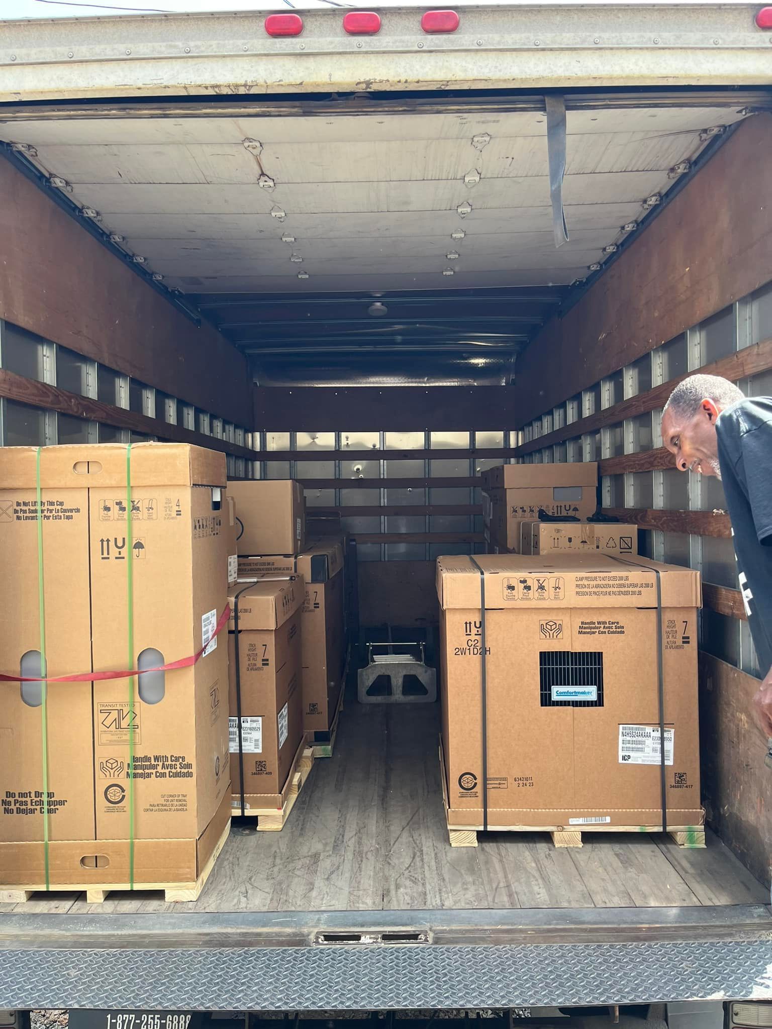 A man is standing in the back of a truck full of boxes