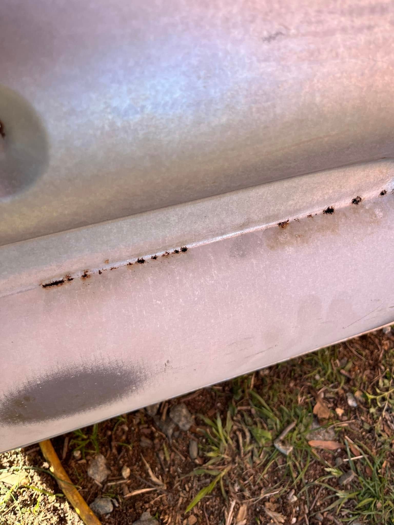 A close up of a metal pipe sitting on top of a grass covered field.