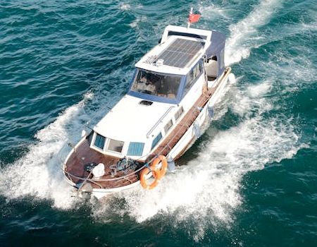 A white and wood-trimmed motor yacht cruises through deep blue water, leaving a white wake behind it.