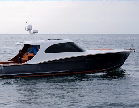 A sleek dark-grey and white yacht cruises on calm, open water.