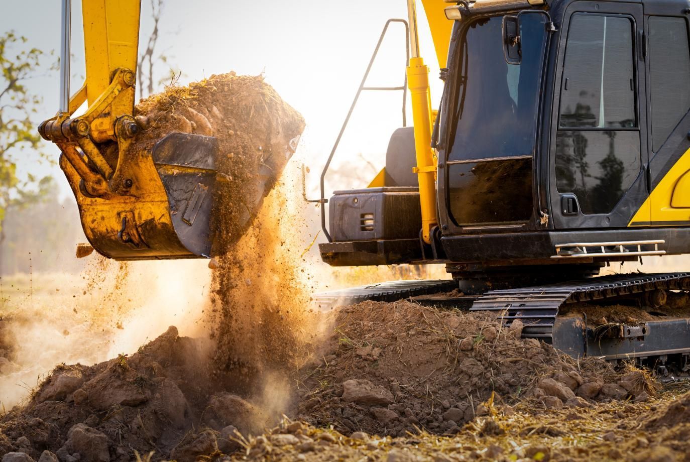 Excavator scooping and dumping dirt at a construction site in warm sunlight