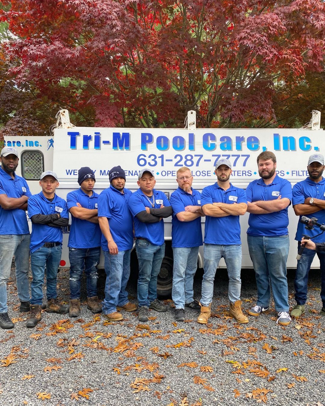 A group of people in matching blue polo shirts stand in front of a white Tri-M Pool Care work van.