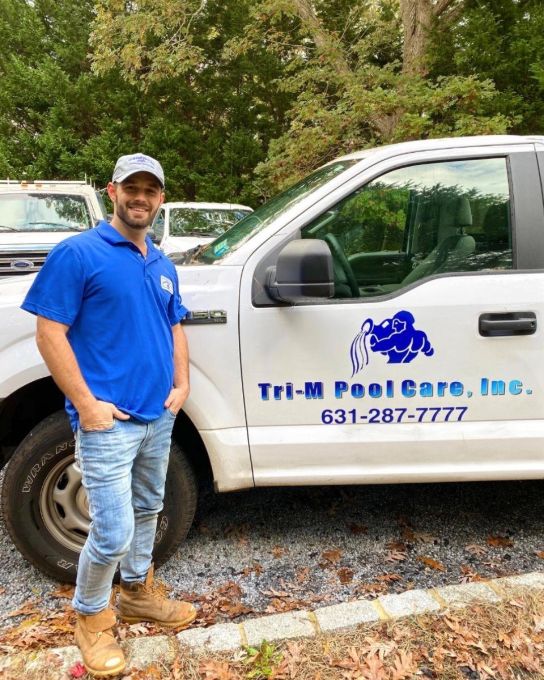 A smiling professional in a blue polo shirt stands next to a work truck labeled 