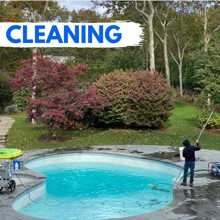 A person stands by a backyard pool holding a long cleaning pole, with a 