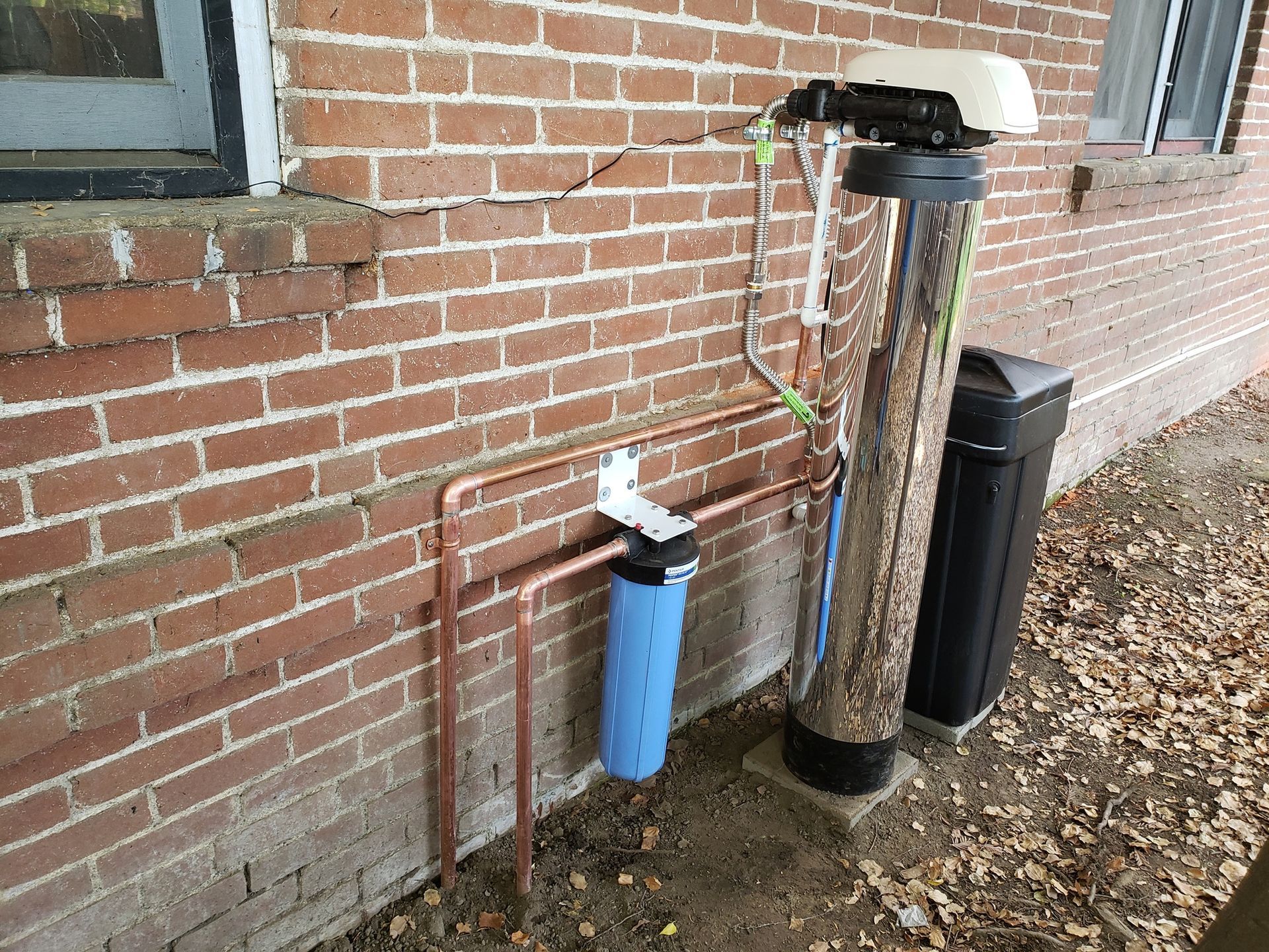 A water filter is attached to the side of a brick building.