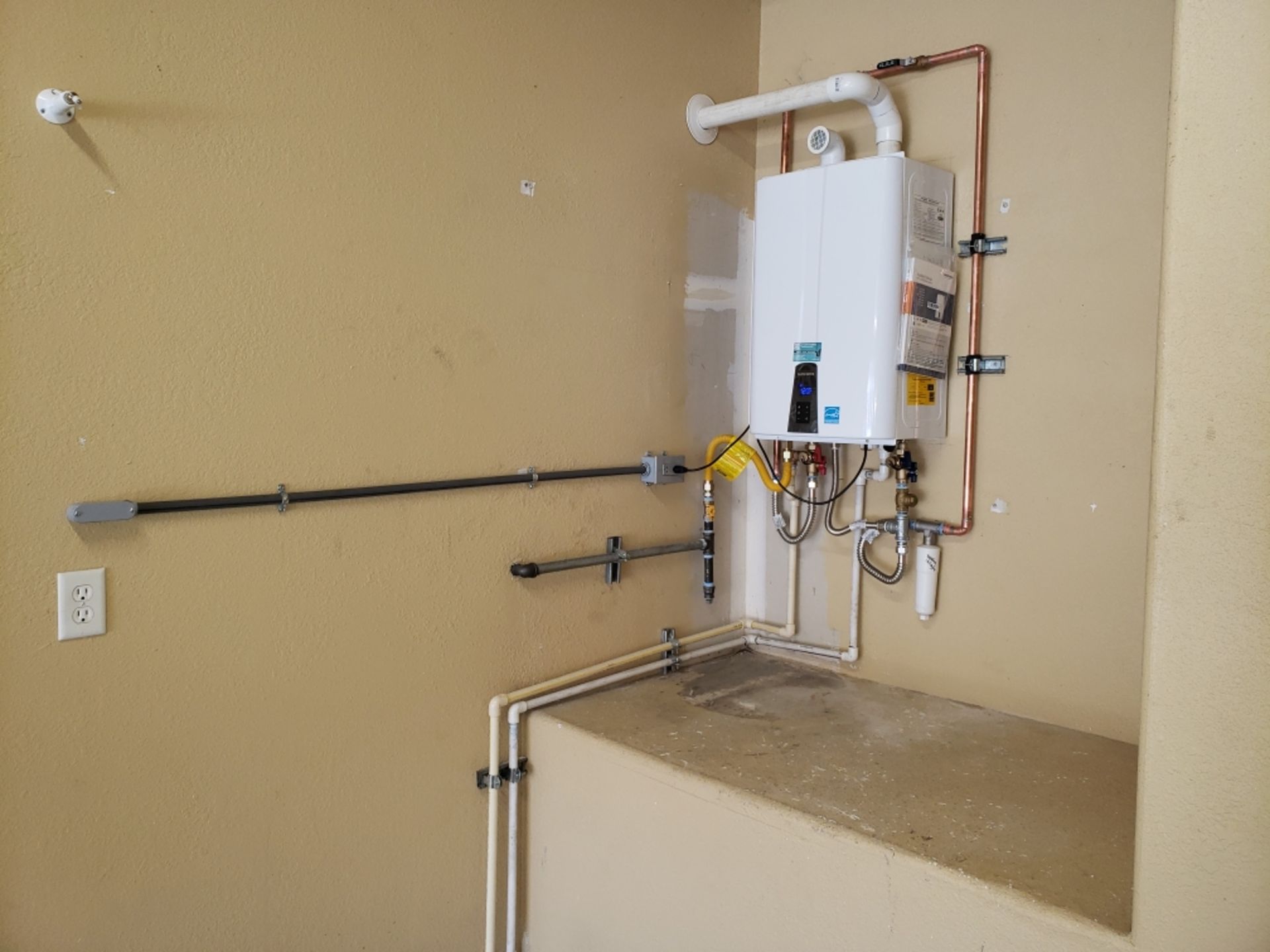 A white water heater is mounted to the wall in a room.