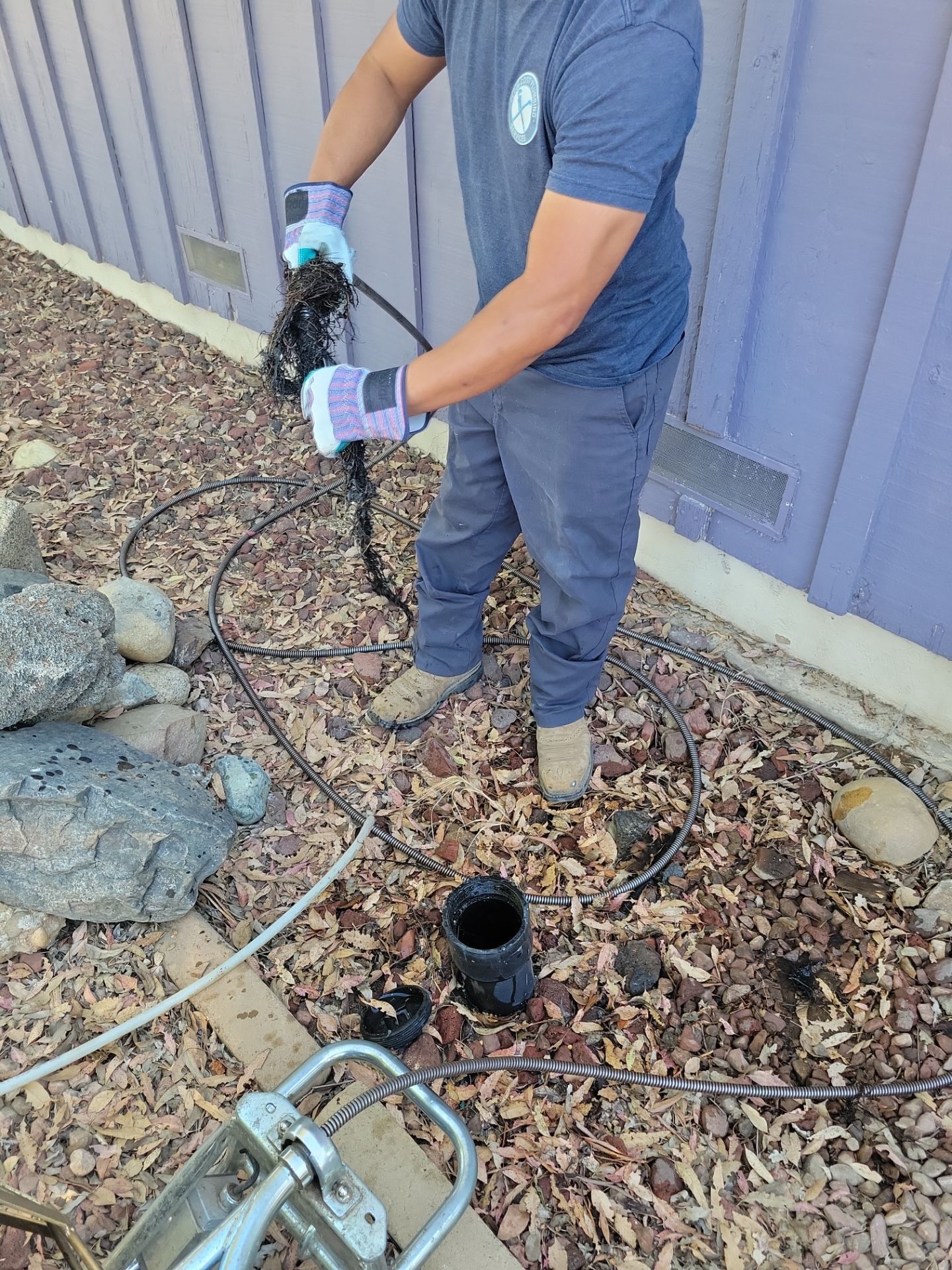 A person is working on a pipe in a muddy area.