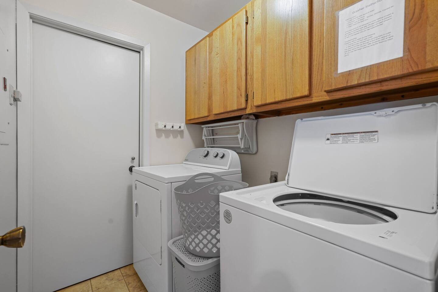 A laundry room with a washer and dryer and a basket.