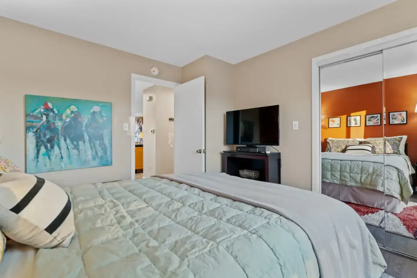 A bedroom with a bed , television , and a painting on the wall.