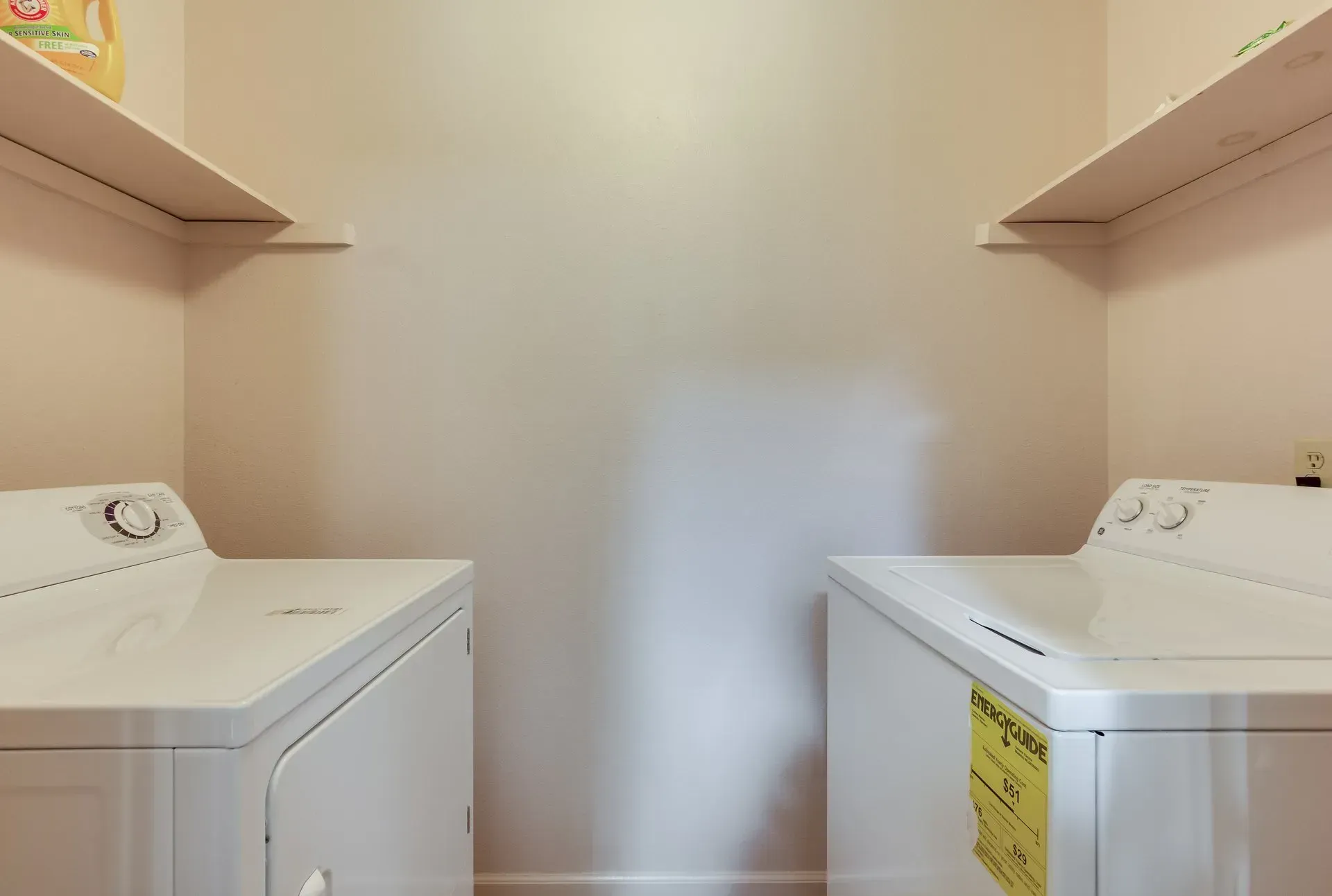 A laundry room with two white washers and dryers.