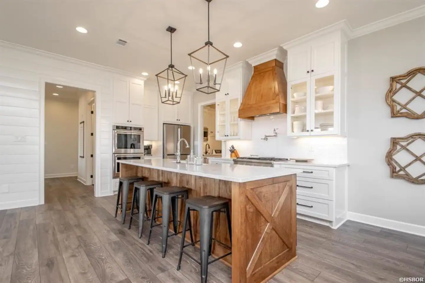 A kitchen with white cabinets and a large wooden island with stools.