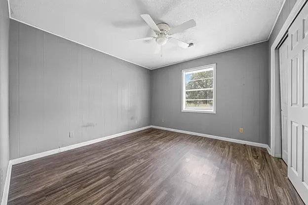 An empty bedroom with hardwood floors and a ceiling fan.