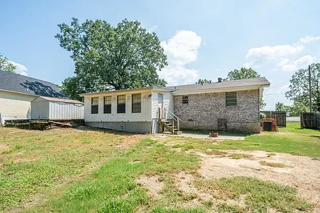 A mobile home is sitting in the backyard of a brick house.