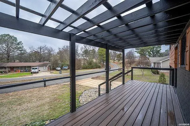 There is a porch with a pergola over it and a view of the street.