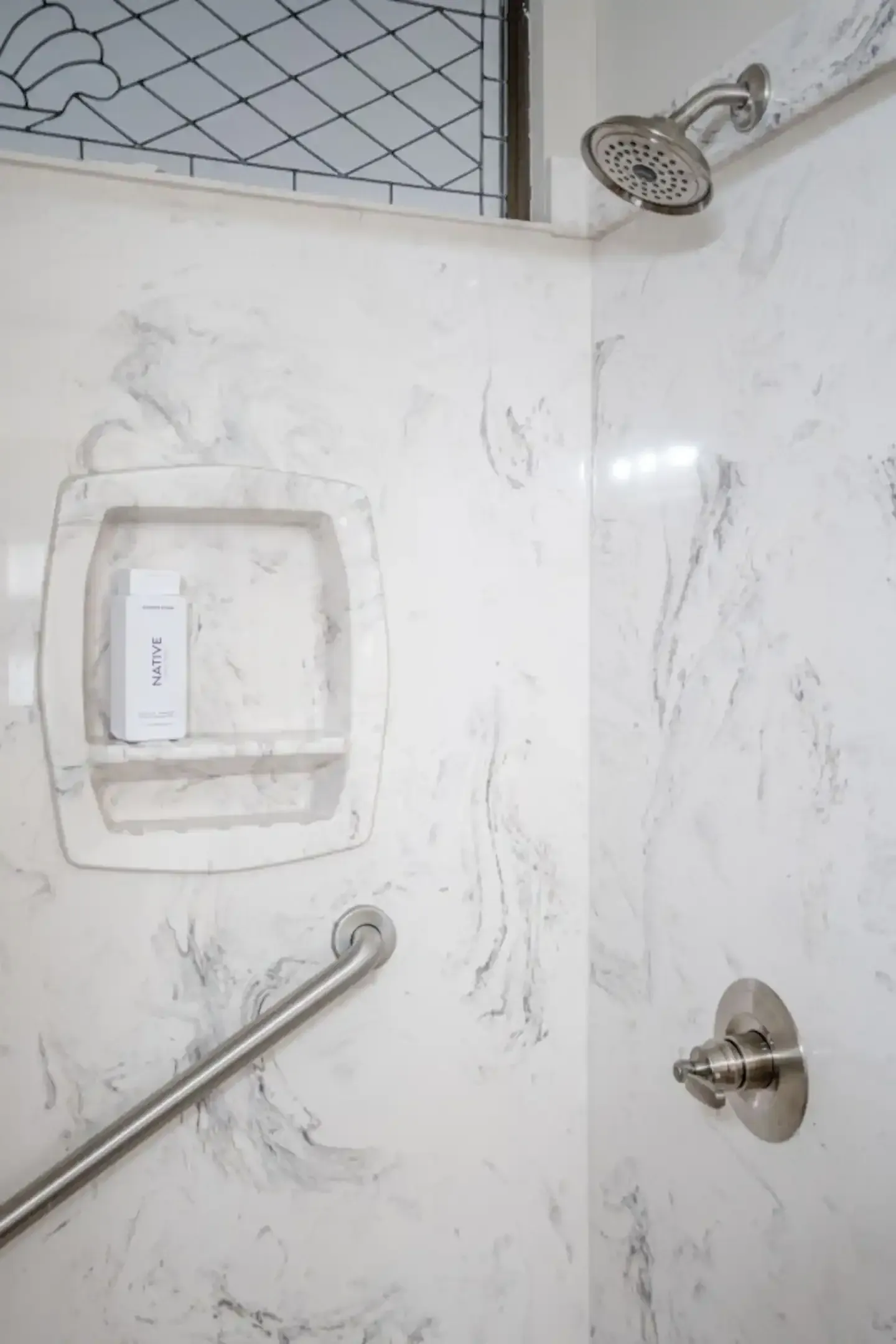 A shower with a hand rail and a shower head.
