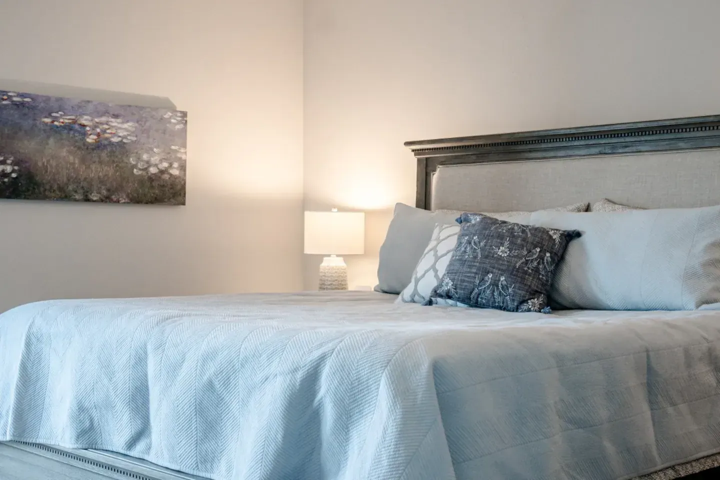 A bedroom with a large bed and a painting on the wall.