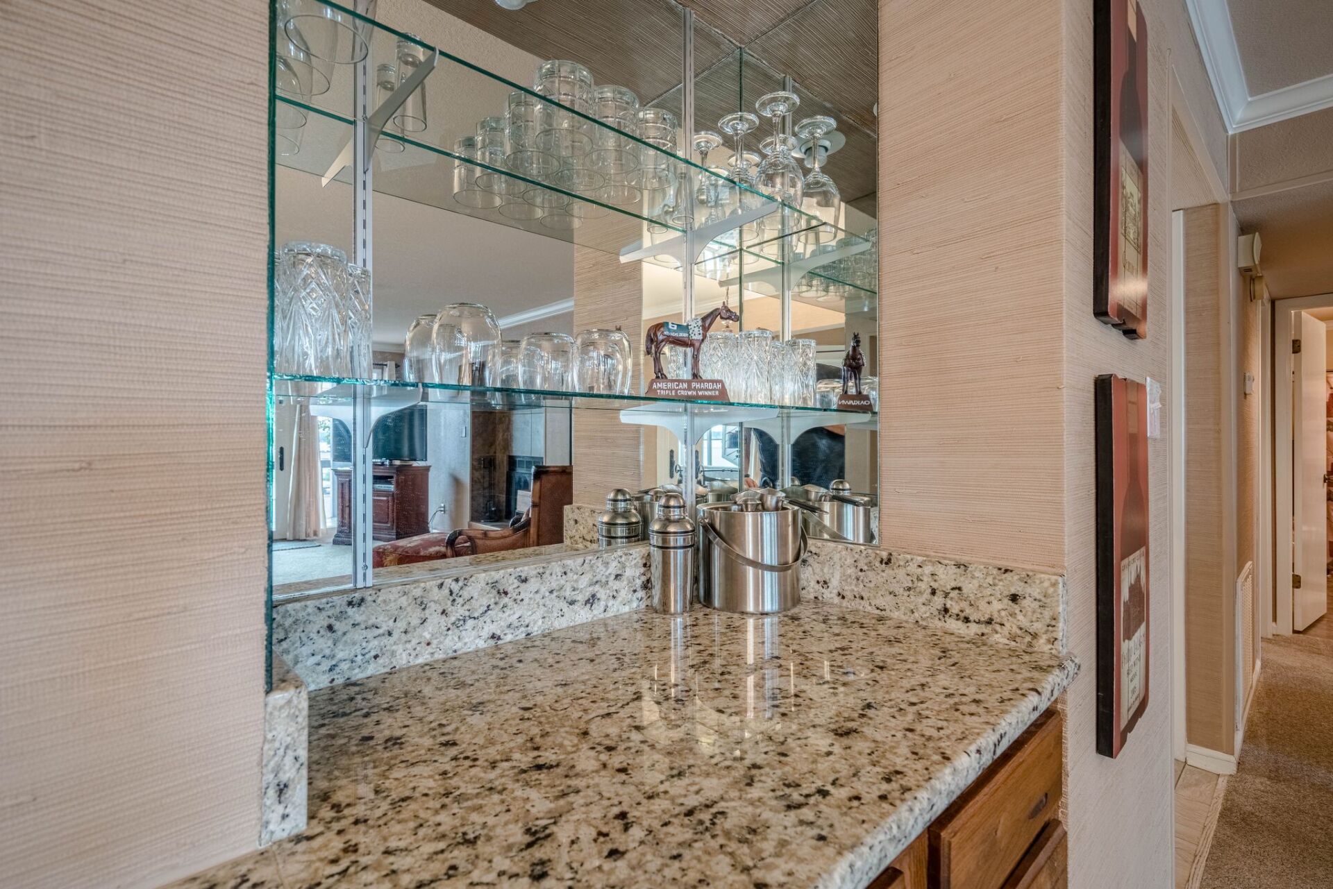 A kitchen counter with a glass shelf and a mirror.