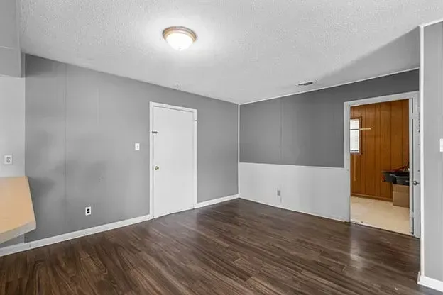 An empty living room with hardwood floors and gray walls.