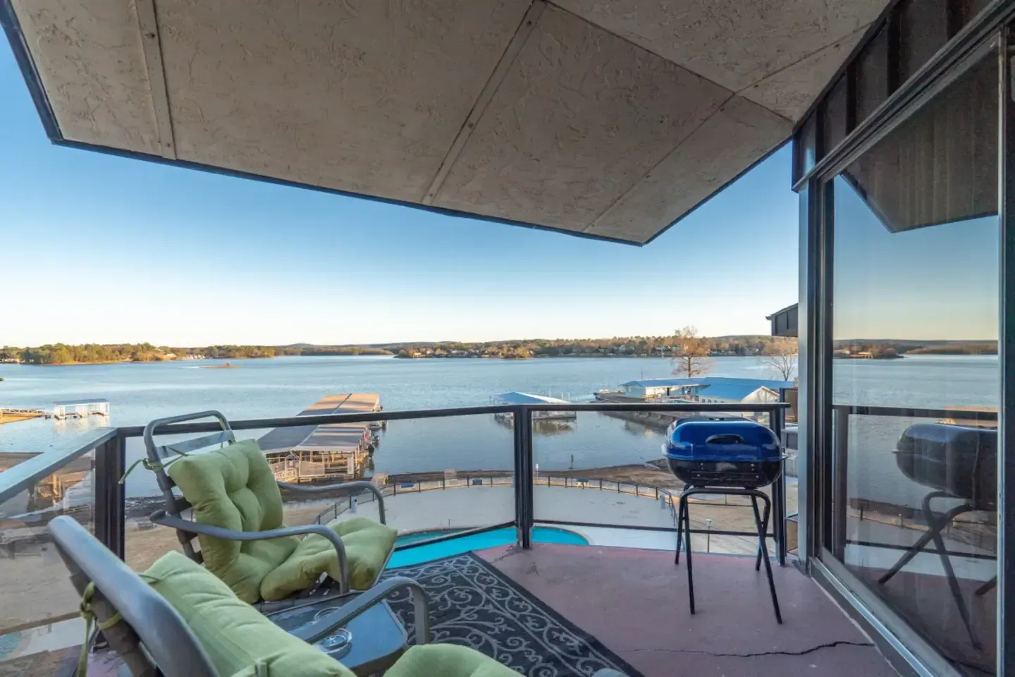 A balcony with a view of a lake and a grill.
