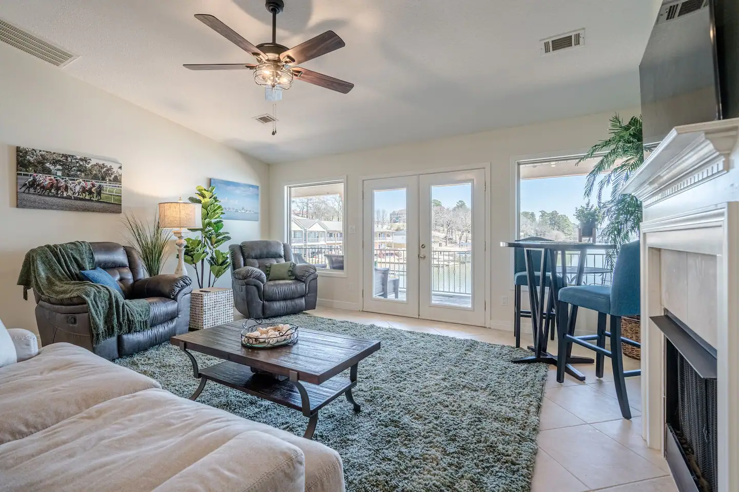 A living room with a couch , chairs , table , fireplace and ceiling fan.