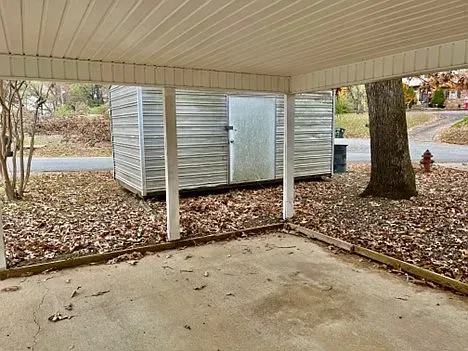 An empty parking lot with a shed and a fire hydrant.