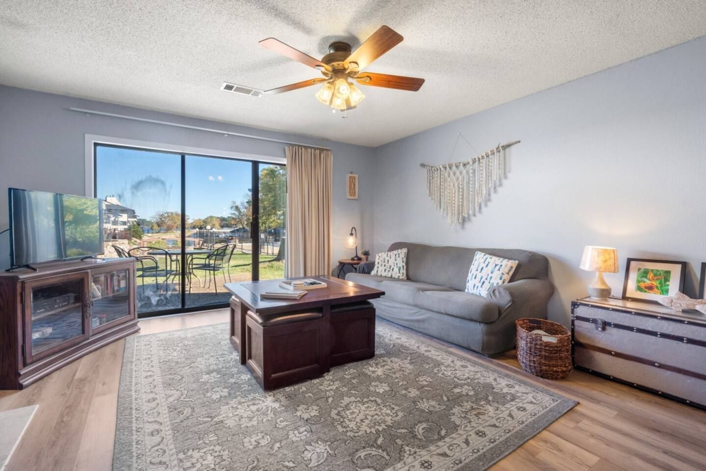 A living room with a couch , coffee table , television and ceiling fan.