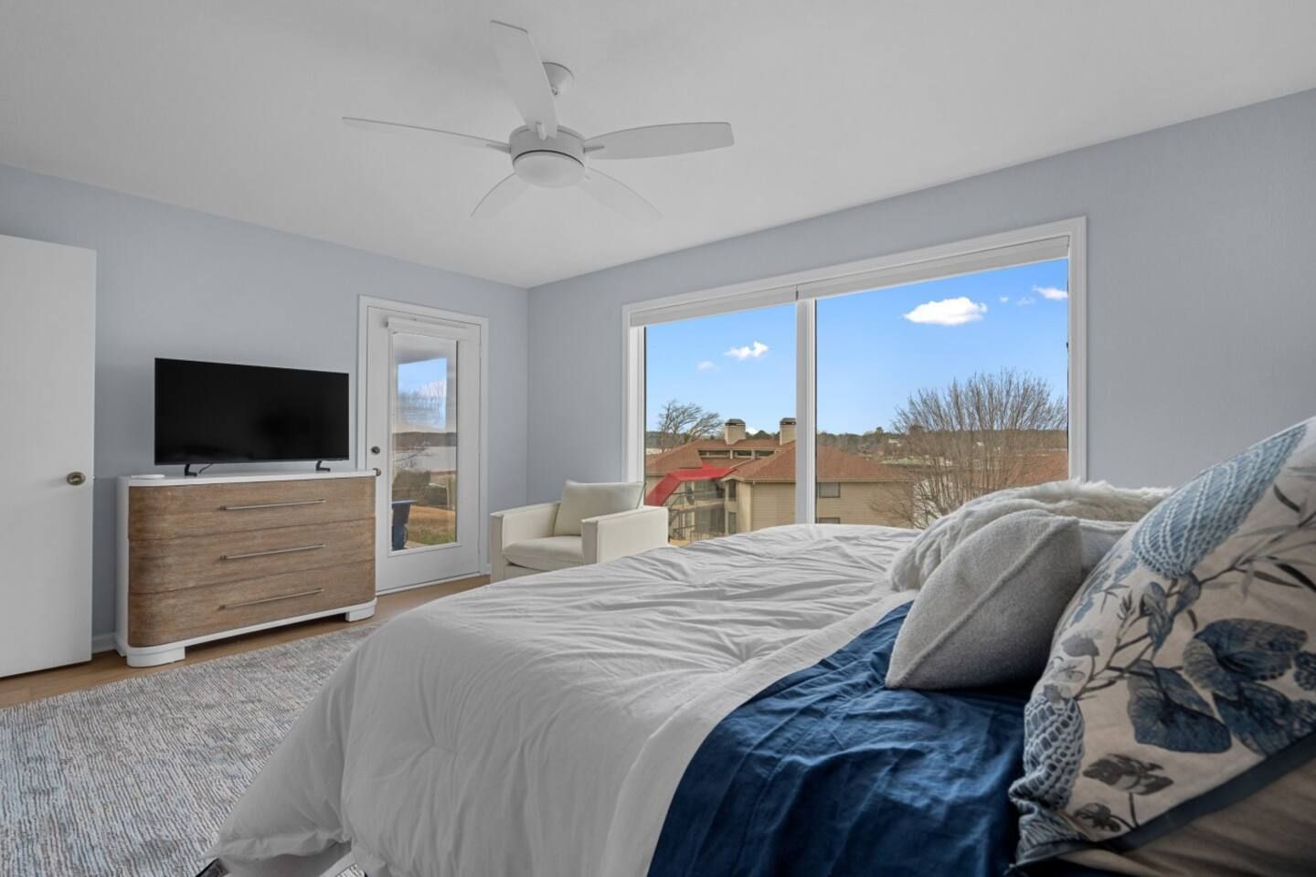 A bedroom with a bed , television , dresser and sliding glass doors.