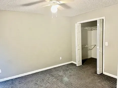 An empty bedroom with a ceiling fan and a walk in closet.