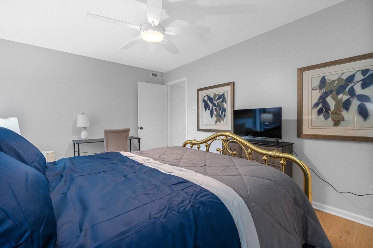 A bedroom with a bed , desk , television and ceiling fan.