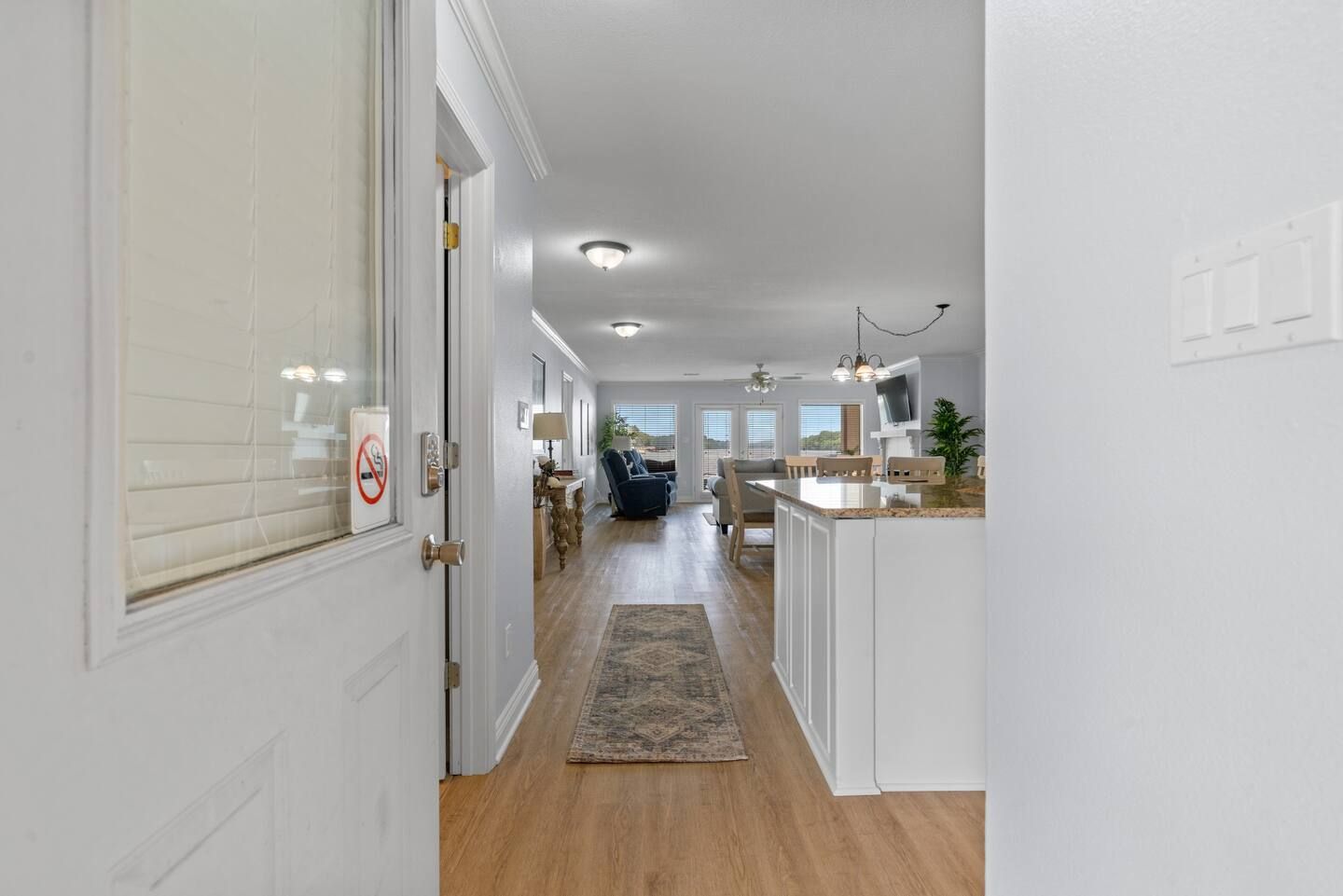A hallway leading to a living room and kitchen in a house.
