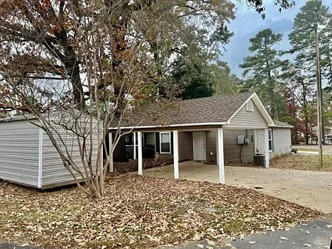 A small house with a porch and a shed in the backyard.